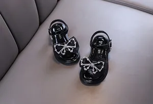 Elegante Mädchensandalen aus schwarzem Lackleder mit funkelnder Strass-Schleife
