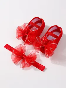 Detailansicht des roten Baby-Sets mit dekorativen Spitzenschleifen und silbernen Sternen.