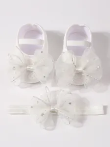 Detailansicht der weißen Babyschuhe und des Stirnbands mit glitzernden Sternenbögen