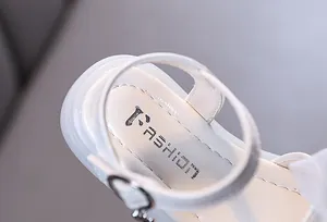 Makro-Detail der weißen Mädchensandalen-Innensohle mit 'Fashion'-Aufdruck und Nähten