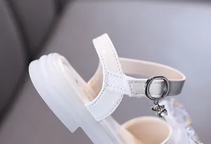 Detailaufnahme einer weißen Lackleder-Sandale für Mädchen mit Strass-Bärenanhänger