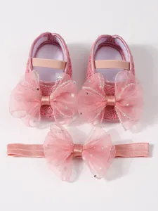 Detailansicht von rosa Baby-Spitzenschuhen und passendem Stern-Pailletten-Stirnband