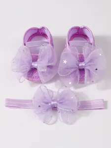 Detail von violetten Spitzen-Babyschuhen und passendem Schleifen-Stirnband-Set.