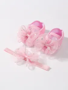 Nahaufnahme von rosa Baby-Prinzessinnenschuhen und passendem Schleifen-Stirnband mit Sternen