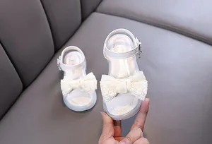Detailed close-up of white girl's princess sandals with an elegant lace bow