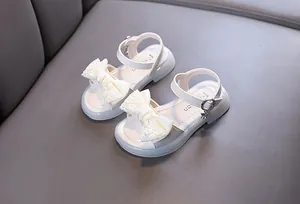 Detailed view of white girls' princess sandals featuring a delicate lace bow and charm