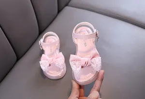 Detailed view of pink toddler girls' sandals featuring a delicate lace bow and buckle.