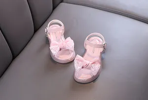 Detailed view of elegant pink girls' princess sandals with a decorative lace bow ornament.