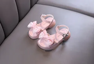 Macro view of pink girls' sandals featuring a delicate lace bow and cute rabbit charm