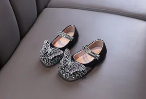 Close-up of girls' black Mary Jane shoes featuring sparkling rhinestone butterfly details.