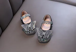 Detailed view of girl's black princess shoes with a large sparkling rhinestone butterfly.