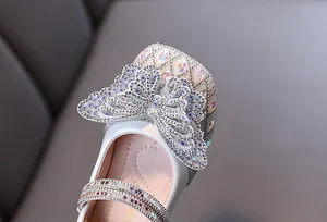 Close-up of girl's white princess shoe with large rhinestone butterfly and sparkling straps.