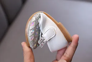 Close-up showing the flexible sole of white girls' rhinestone princess flat shoes