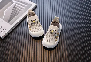 Close-up of beige breathable mesh fly-knit slip-on shoes for toddlers with cute bear patch