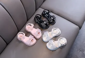 Detalle de sandalias de princesa con lazo de pedrería para niñas en tres colores.
