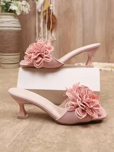 Dettaglio di sabot rosa eleganti con fiore in tessuto 3D e punta quadrata alla moda.