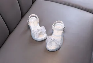 Vista detallada de sandalias blancas de princesa con lazo de diamantes y correa hebilla