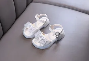 Vista detallada de sandalias de princesa blancas para niña con lazo de diamantes.