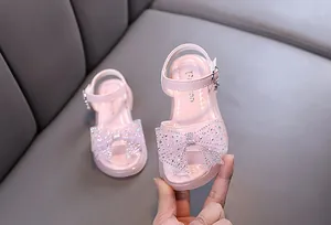 Primer plano de sandalias de princesa rosas para niña con un lazo grande con pedrería