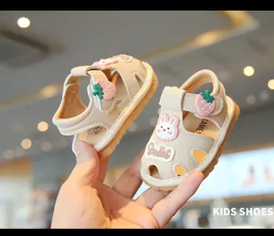 Primer plano de lindas sandalias beige para bebé con parches de fresa y conejo