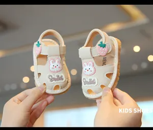 Primer plano de sandalias de verano para bebé con detalles de conejo y fresa