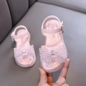 Elegantes sandalias de princesa rosas para niñas con detalle de lazo de diamantes brillantes.
