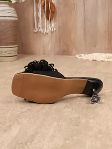 Primo piano della suola beige antiscivolo e del tacco a spillo trasparente di un sandalo.