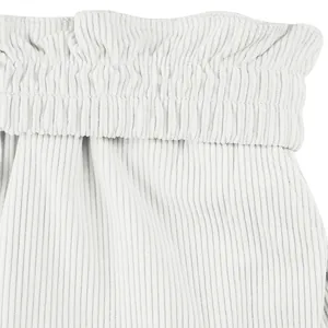 Detailed macro view of the white corduroy fabric and elasticated ruffled waistband