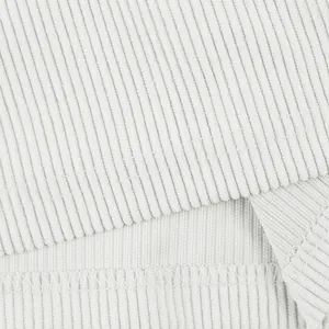 Macro view of white ribbed corduroy fabric and reinforced stitching for sports shorts.