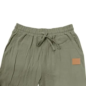 Close-up detail of men's olive green linen pants featuring elastic waist and drawstring.