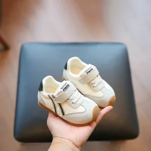 Breathable white and grey toddler walking shoes with velcro strap held in hand.