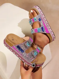 Close-up detail of pink platform sandals with sparkling rhinestones and cork soles for summer.