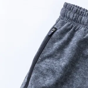 Close-up view of side zipper pocket and elastic waistband on grey heather terry sports shorts.