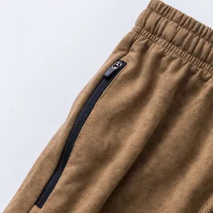 Detailed close-up of zipper pocket and elastic waist on men's brown Terry sports shorts.