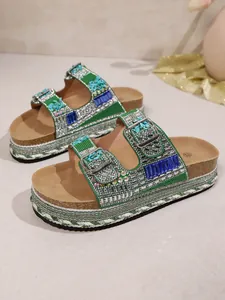 Close-up of green rhinestone platform slides featuring braided rope and cork sole.