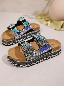 Close-up detail of sparkling rhinestone sandals with blue gems and a cork platform sole.