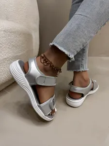 Vue détaillée de sandales compensées argentées avec brides velcro portées sur les pieds