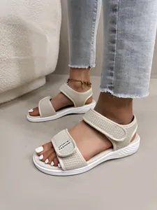 Gros plan de sandales de sport en maille beige avec velcro portées aux pieds
