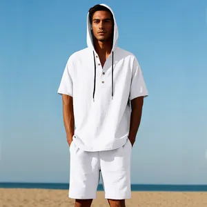 Uomo che indossa un set camicia con cappuccio in lino bianco e pantaloncini sulla spiaggia