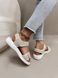 Gros plan de sandales de sport en maille beige pour femme avec semelles plateforme à vagues.