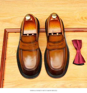 Bovenaanzicht van bruine leren penny loafers met schoenspanners en een vlinderdas