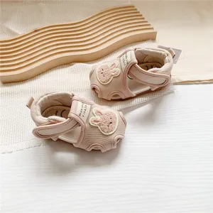 Close-up of pink baby sandals with cute cartoon rabbit patch and soft fabric detail