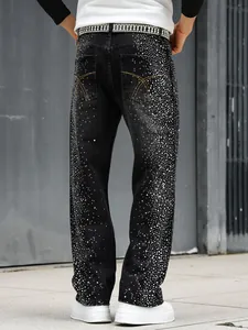 Détail d'un jean noir coupe droite pour homme avec des ornements en strass brillants.