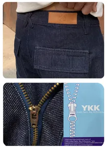 Close-up detail of dark blue washed denim jeans with YKK zipper and leather patch