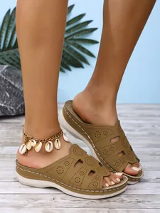 Gros plan de sandales compensées marron pour femmes avec des motifs de découpes florales