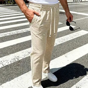 Detailopname van een beige geruite herenbroek met trekkoord op een zebrapad.