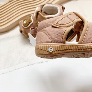 Close-up of brown baby squeaky sandals with cartoon bear patch detail