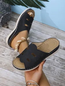 Gros plan de sandales compensées noires pour femmes avec motifs circulaires ajourés