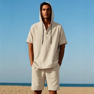 Completo uomo in lino beige con camicia con cappuccio e pantaloncini sulla spiaggia.