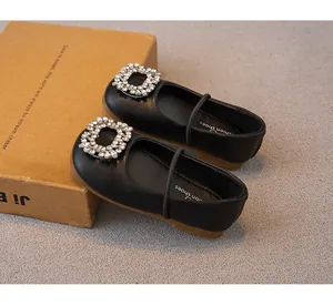 Nahaufnahme von schwarzen Prinzessinnenschuhen für Mädchen mit Kristallschallen.